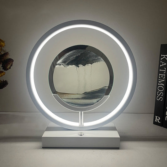 This decorative round flowing ornamental table lamp features the dynamic nature of the quicksand by incorporating elements that suggest movement, such as swirling patterns, tilted angles, or uneven shapes for a contemporary abstract touch.